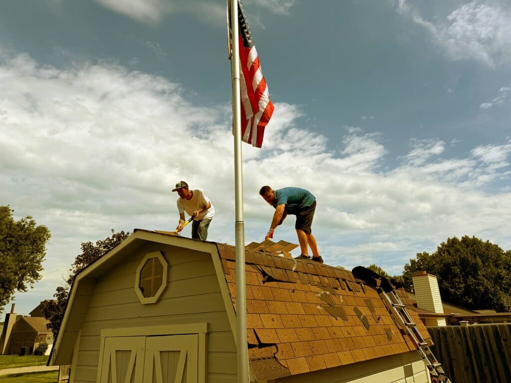 Pristine Roofing crew replacing a roof with the American flag flying