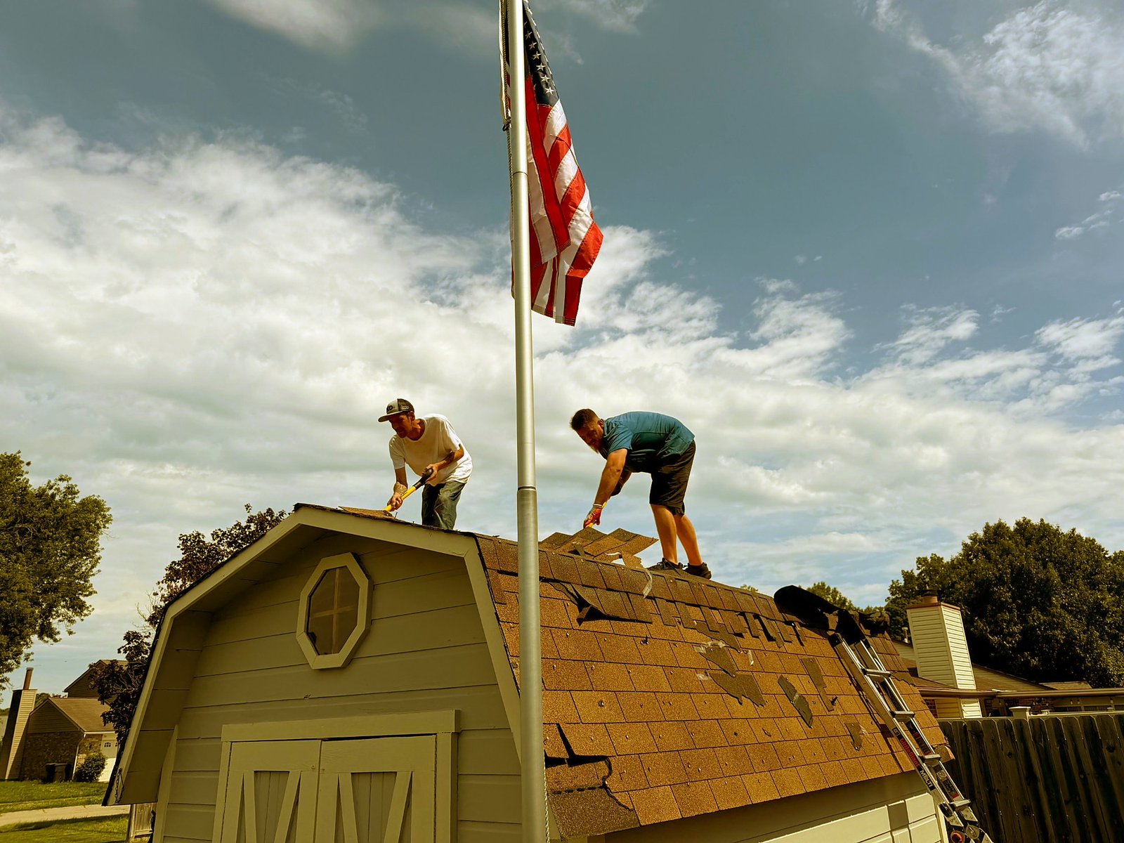Pristine Roofing crew replacing a roof with the American flag flying